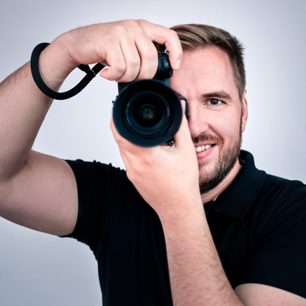 Selbstportrait des Fotografen Dominique Lackmann mit einer Kamera in der Hand