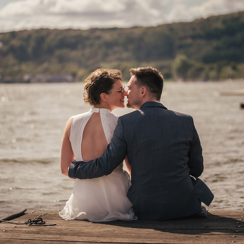 Brautpaar sitzt am Steg des Baldeneysees in der Nähe der Südtiroler Stuben an Ihrem Hochzeitstag. Heiraten in Essen am Baldeneysee.