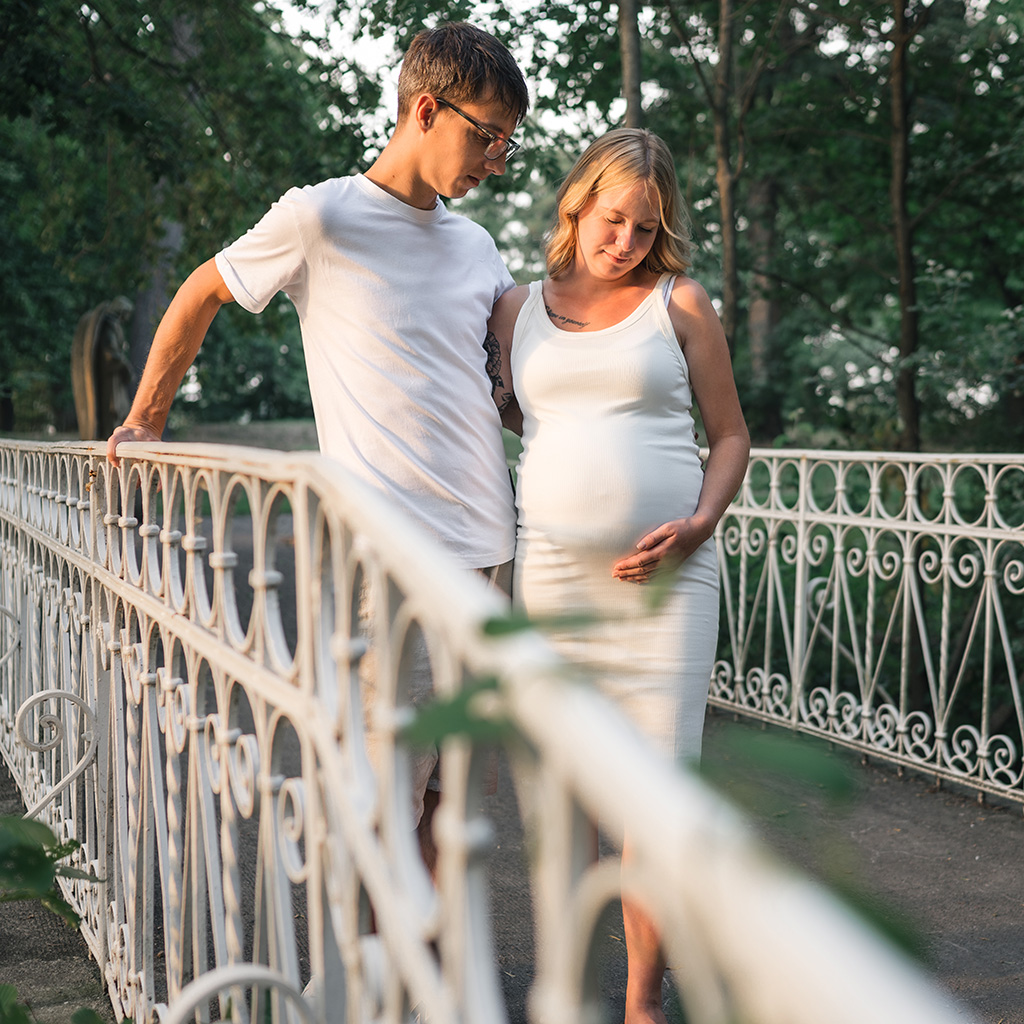 Paar steht an einer Brücke während des Babybauchshootings am Haus Aspel in Rees, NRW. Niederrhein.